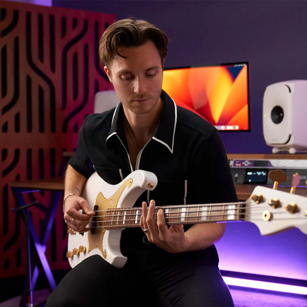 Man playing bass guitar in a recording studio.